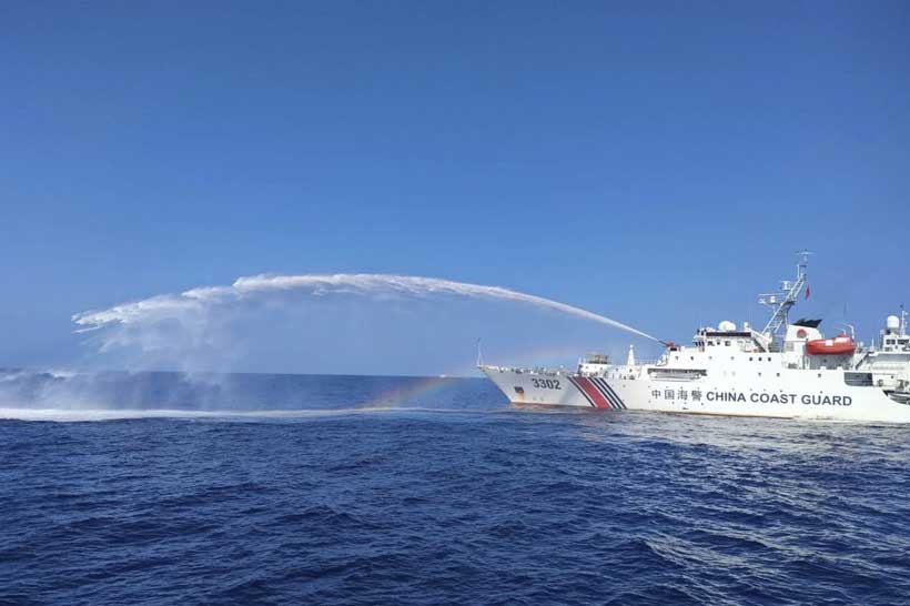 Chinese coast guard vessel using a water cannon against a Philippine supply boat near Second Thomas Shoal in the South China Sea — one of dozens of documented incidents in 2025
